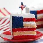 A vibrant and patriotic American Flag Cake stands proudly, showcasing its layers of red, white, and blue. The cake is adorned with meticulous details, from the precisely decorated stars on the blue rectangle to the luscious berries accentuating the red and white stripes. This delectable masterpiece captures the essence of celebration, inviting you to indulge in a slice of delicious history and national pride.