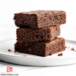 A close-up view of freshly baked brownies with a glossy, cracked surface, emitting a rich aroma of chocolate goodness.