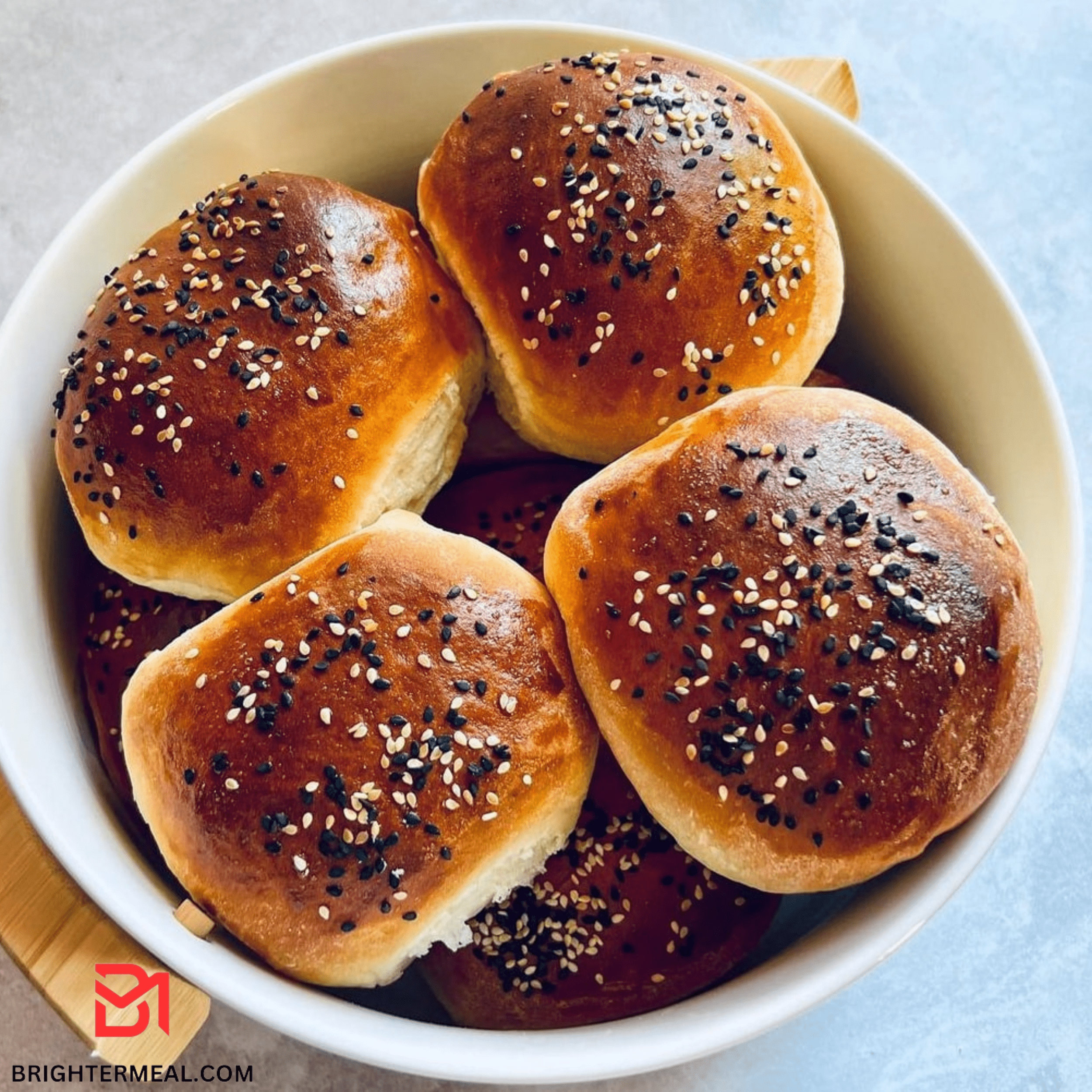 A batch of freshly baked soft bread rolls on a cooling rack.