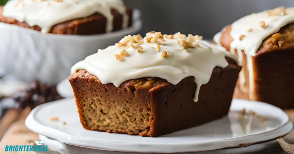 A slice of banana bread topped with creamy frosting on a white plate