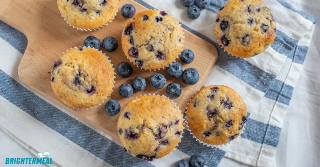 Fresh blueberries scattered next to mini muffins.