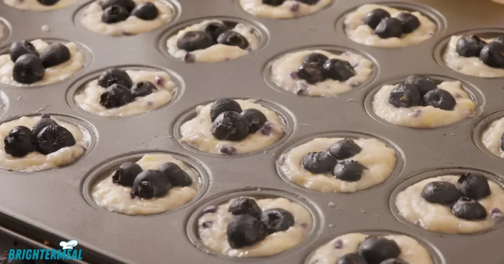 Mixing bowl with muffin batter and fresh blueberries on the side.