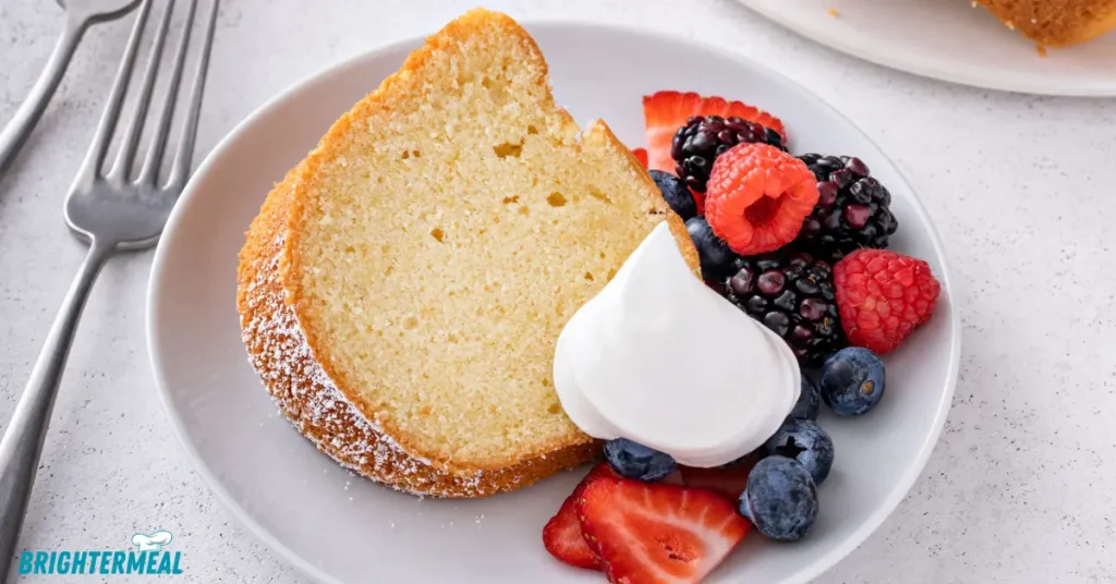 Vanilla pound cake slice on a white plate with fresh strawberries