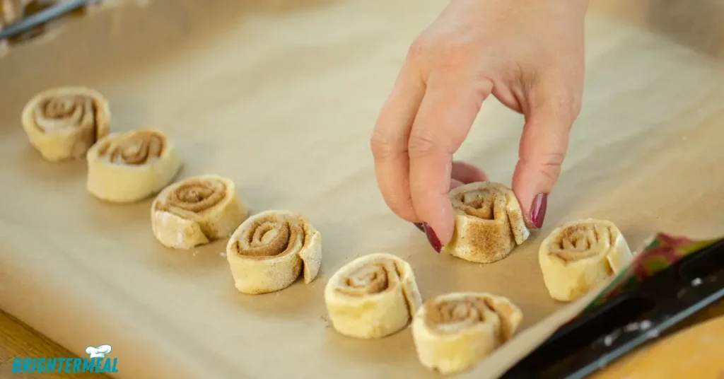 Cream cheese icing being spread over warm rolls