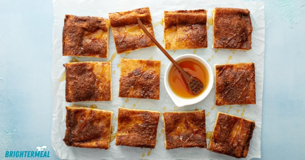 Freshly baked churro cheesecake bars on a baking pan.
