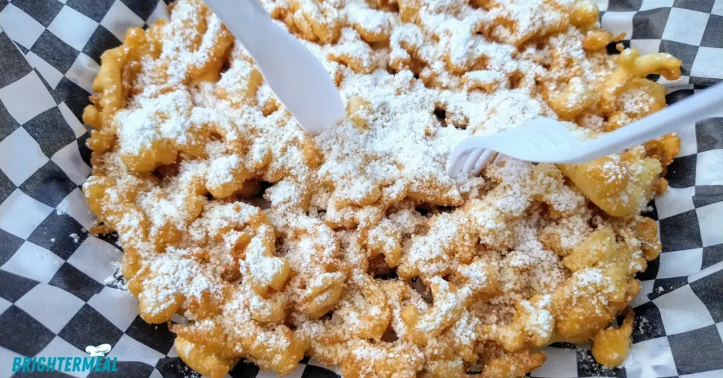 Freshly fried funnel cake on a paper towel-lined plate