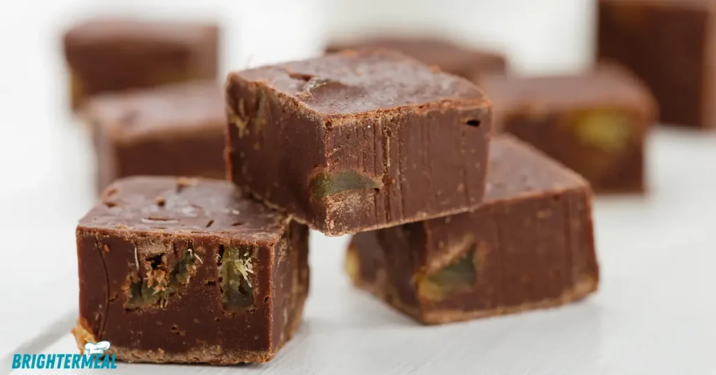 Fudge squares with chopped nuts on a serving plate.