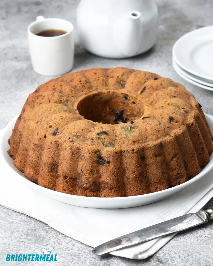Whole banana Bundt cake displayed on a cake stand with a glossy chocolate ganache