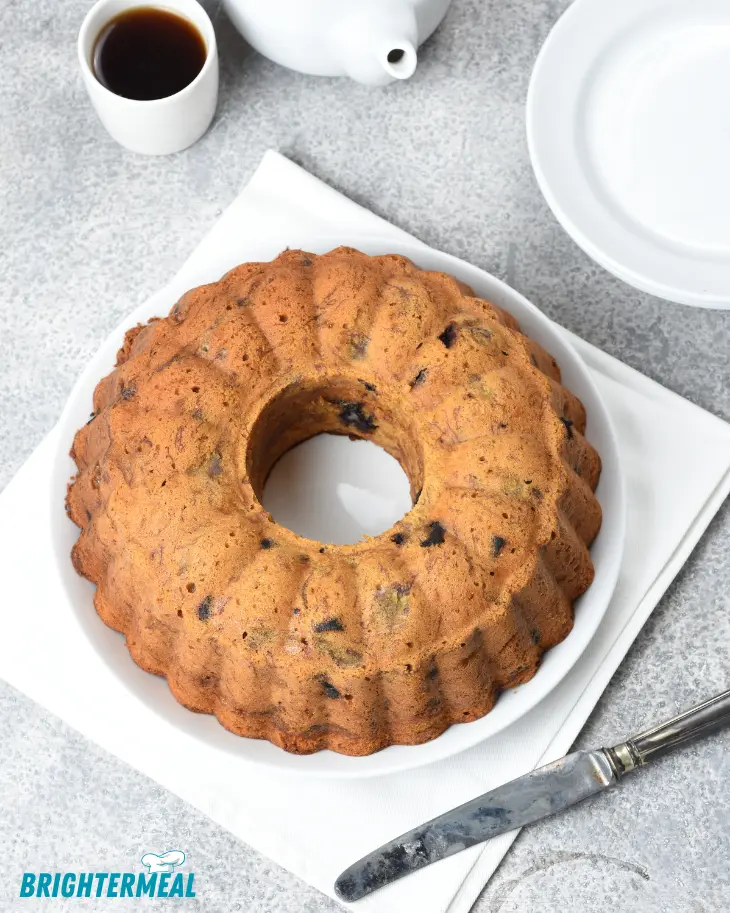 Freshly baked banana Bundt cake drizzled with vanilla glaze on a white plate