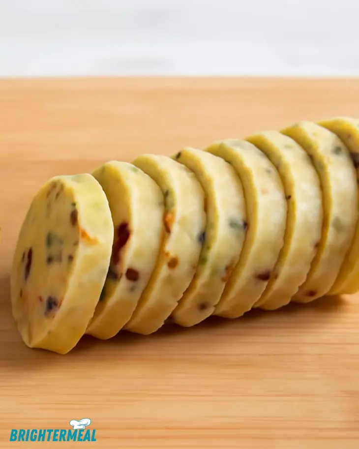 Chilled log of shortbread dough on parchment paper, ready to slice.