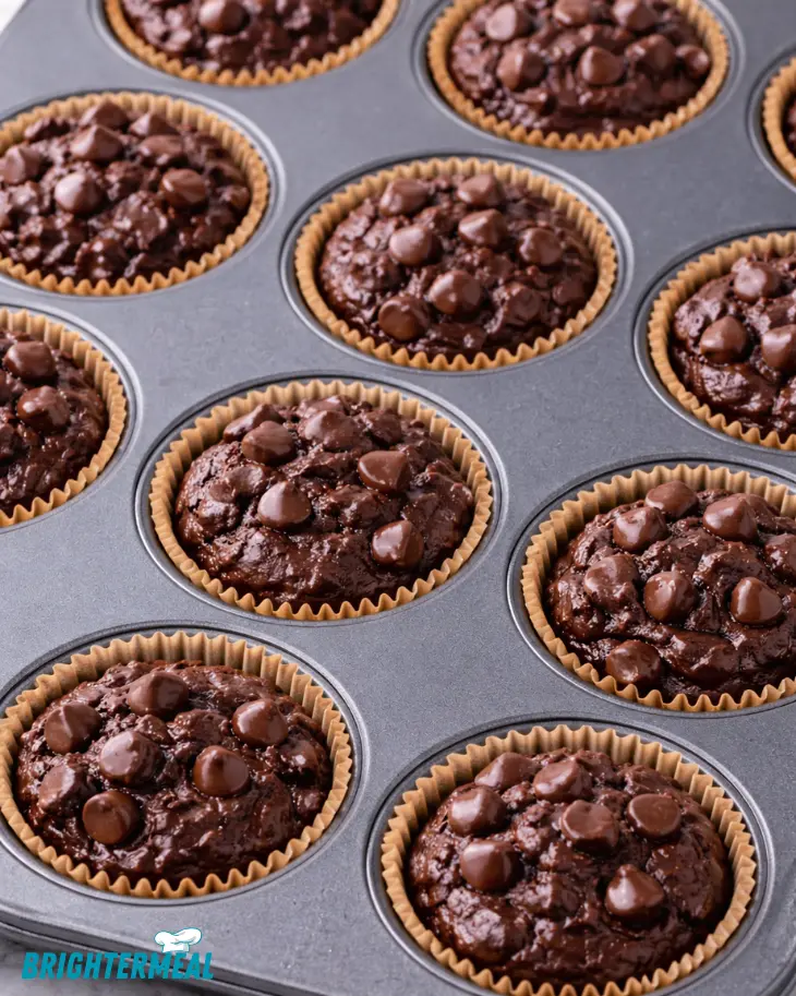 chocolate batter portioned into lined muffin pan